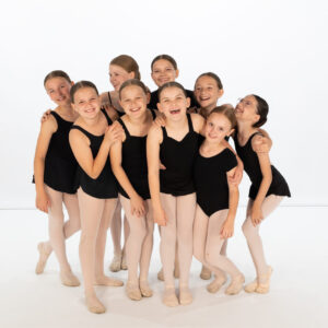 Recital Package for One Student 6 Two students smile as they pose in black leotards, white tights, and ballet slippers, showcasing the Recital Package for Two Students against a plain white background.