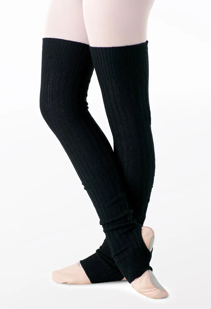 A dancer wearing pale pink tights and shoes stands with crossed legs, showcasing Adult Tall Leg Warmers in black ribbed knit that cover her legs from thigh to ankle.