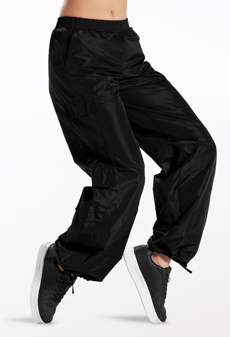 A person wearing Low Rise 4 Pocket Cargo Hip Hop Pants and black sneakers is shown in mid-motion against a white background. The cargo pants feature an elastic waistband and gathered cuffs at the ankles.