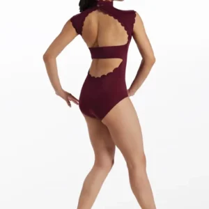 A woman with long dark hair in a ponytail models the Scallop Trim Mock Neck Leotard in burgundy, featuring scalloped edges and an open back. She stands on one leg, facing away with her left leg bent and arms relaxed at her sides.